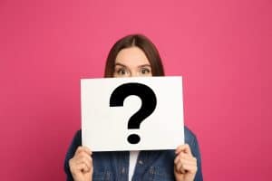 Woman holding question mark sign on pink background