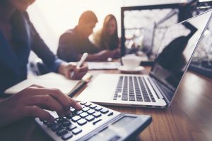 The hands of a female accountant are using a calculator to calculate taxes.